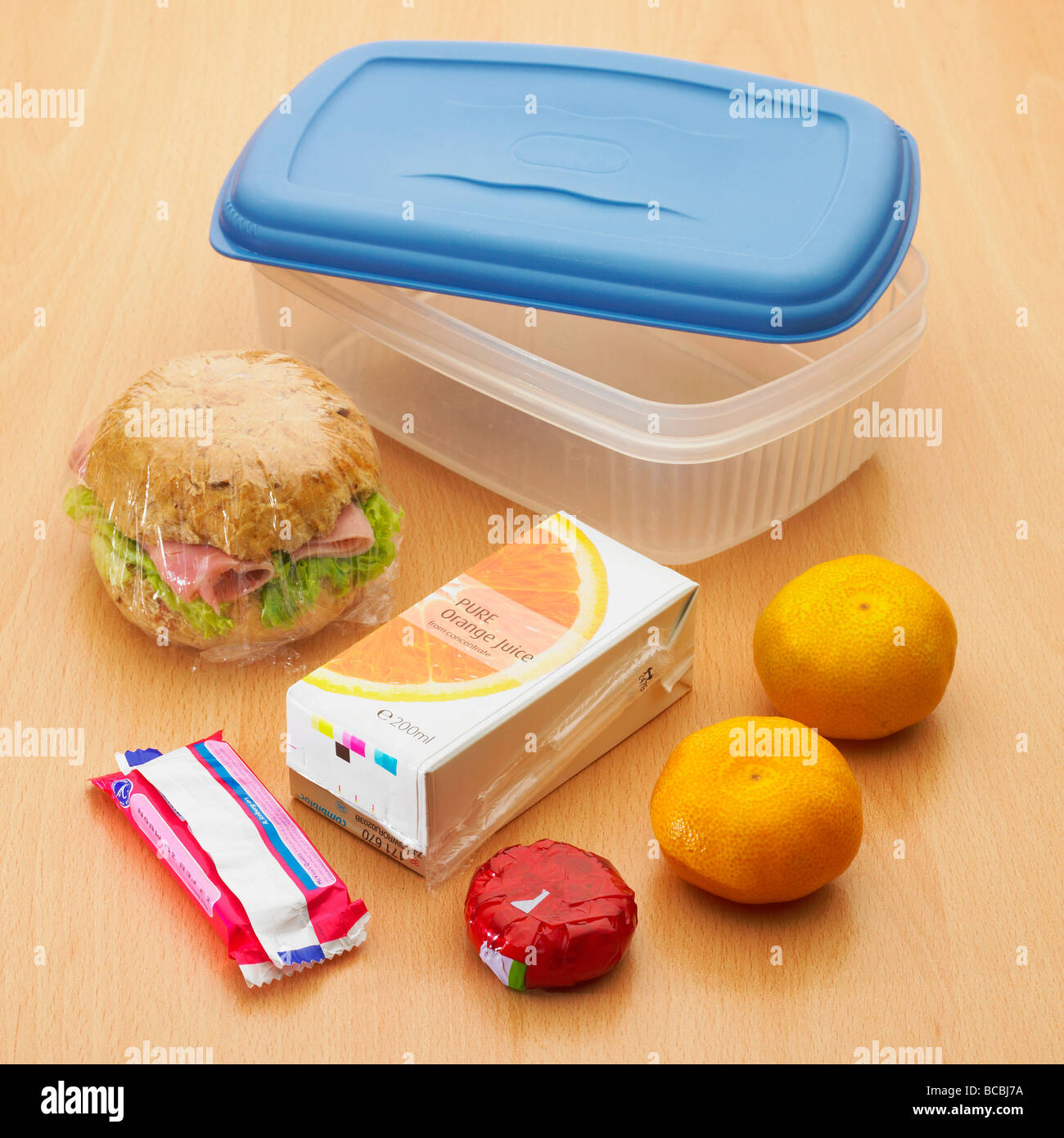 Gesunde Lunchbox mit Vollkornbrötchen, Satsumas / Obst, Mini-Käse, Orangensaft und Keks und Kunststoff-Lunchbox - Schulpaket Mittagessen Stockfoto