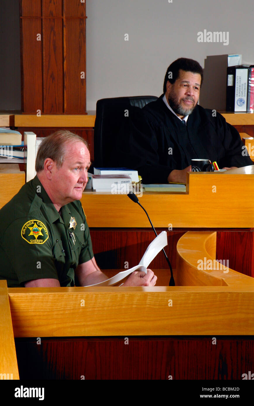 Als ein afrikanischer amerikanischer Richter hört zeugt ein stellvertretender Sherrif in einem Gerichtssaal Southern California Stockfoto