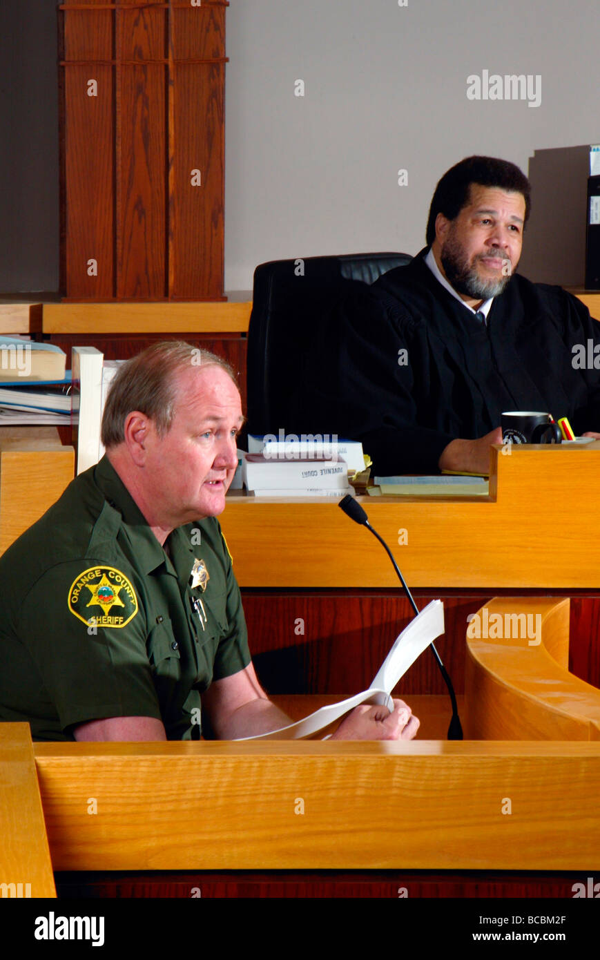 Als ein afrikanischer amerikanischer Richter hört zeugt ein stellvertretender Sherrif in einem Gerichtssaal Southern California Stockfoto