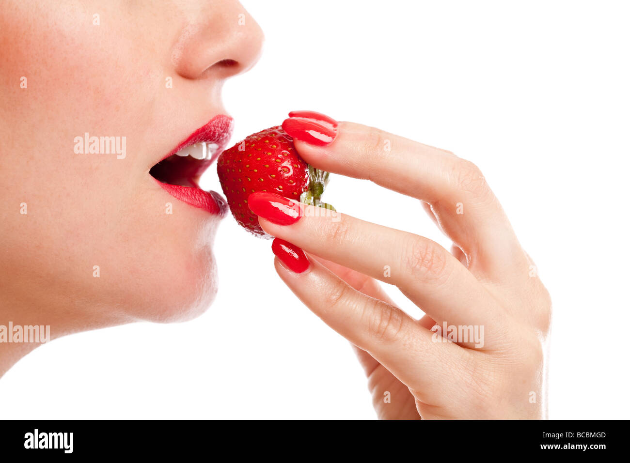 Schöne Frau, die eine Reife rote Erdbeere zum Anbeißen Stockfoto
