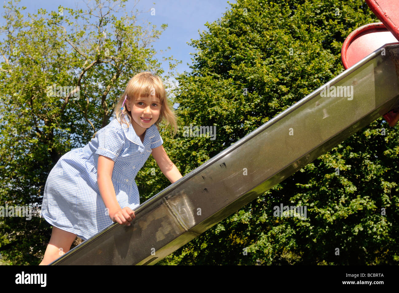 Ein sechs Jahres altes Mädchen klettert auf einer Folie in den park Stockfoto