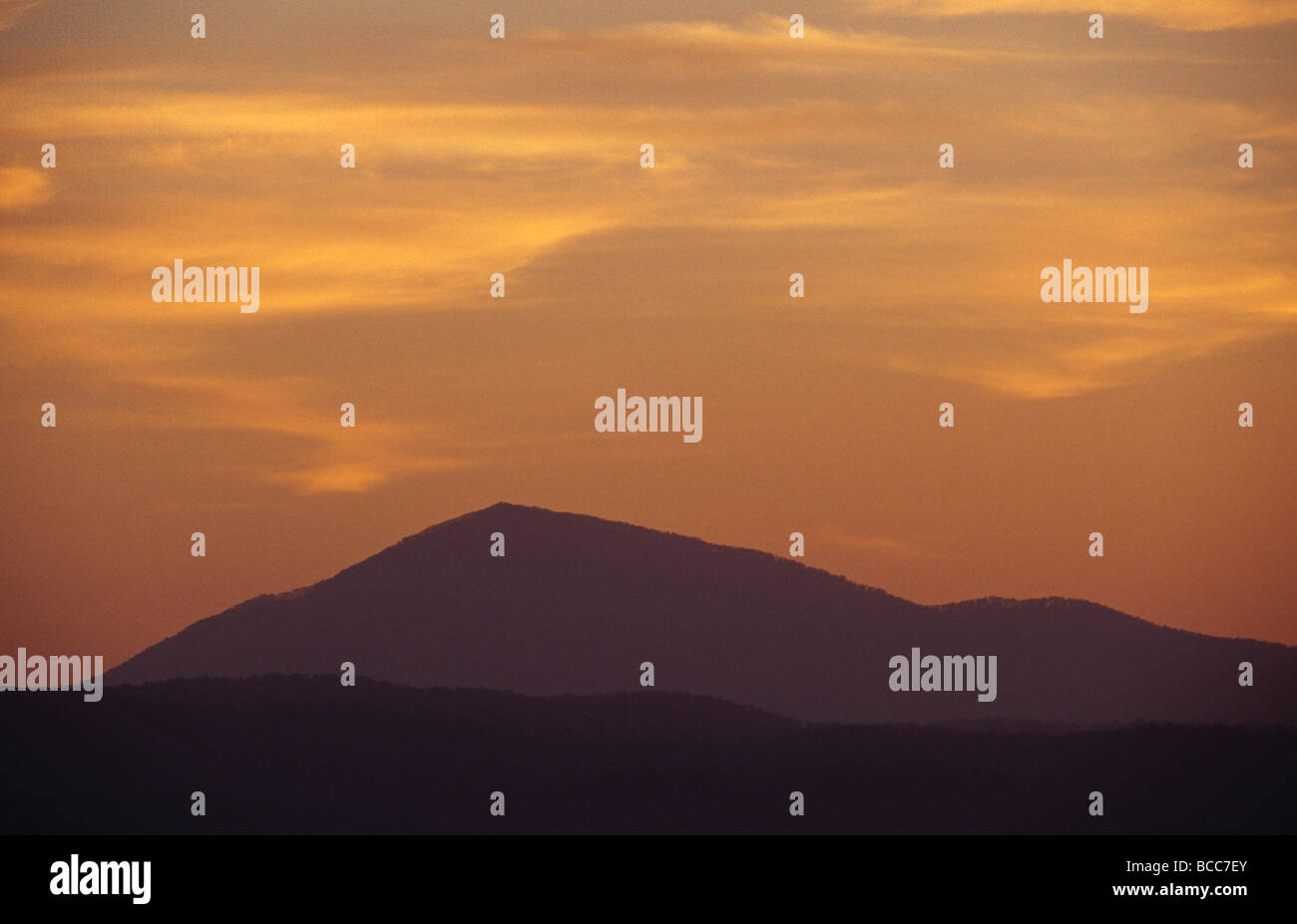 Die Silhouette eines steilen Berges gegen einen spektakulären Sonnenuntergang. Stockfoto