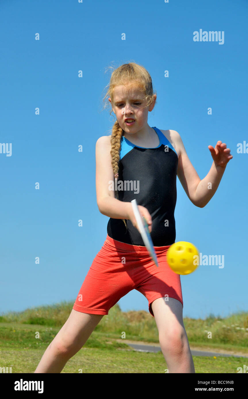 Ein junges Mädchen trifft wieder einen Ball mit einem Schläger. Stockfoto