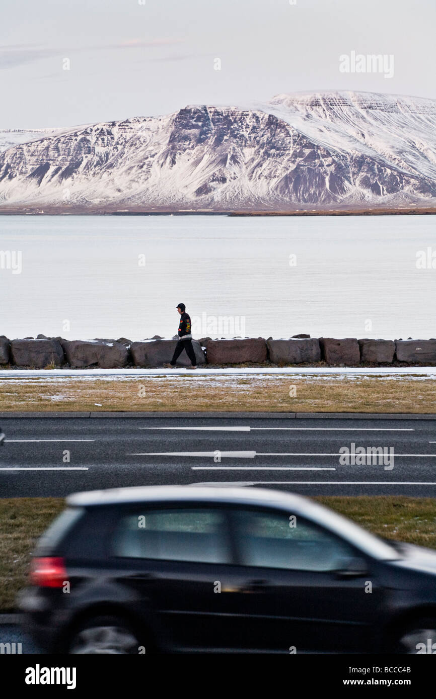 Person zu Fuß an einem kalten Nachmittag, Auto vorbeifahren Stockfoto