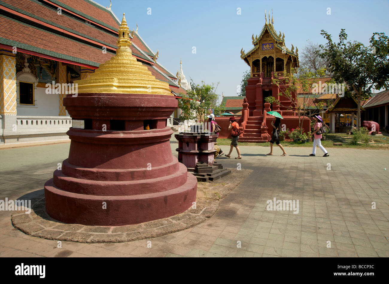 Thailändische Besucher spazieren durch das Gelände des Lamphun's Wat Phra That Haripunjaya Buddhist Temple Stockfoto