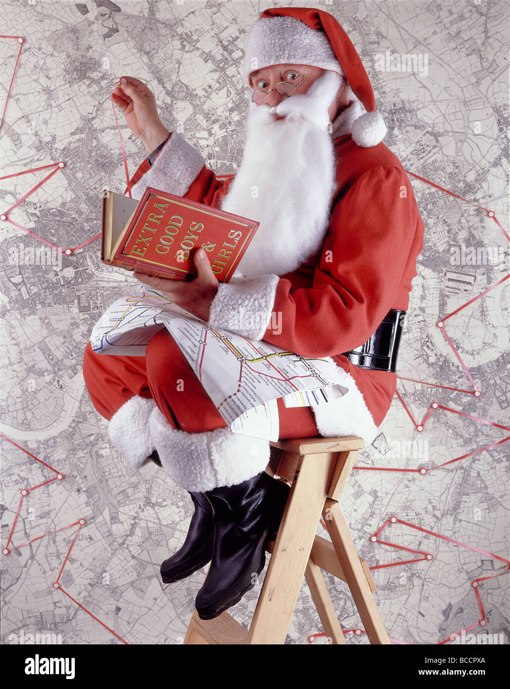 Santa Claus (oder Weihnachtsmann) gegen Karte und Buch mit dem Titel "EXTRA guten jungen & Mädchen" Stockfoto