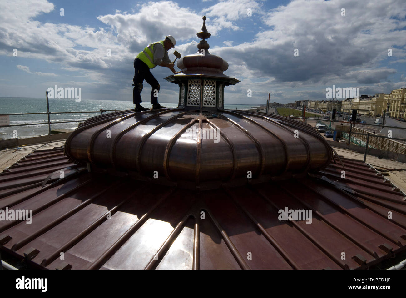 Ein Arbeiter hämmern ein neues Kupferdach auf einen viktorianischen Musikpavillon auf Brighton und Hove direkt am Meer Stockfoto