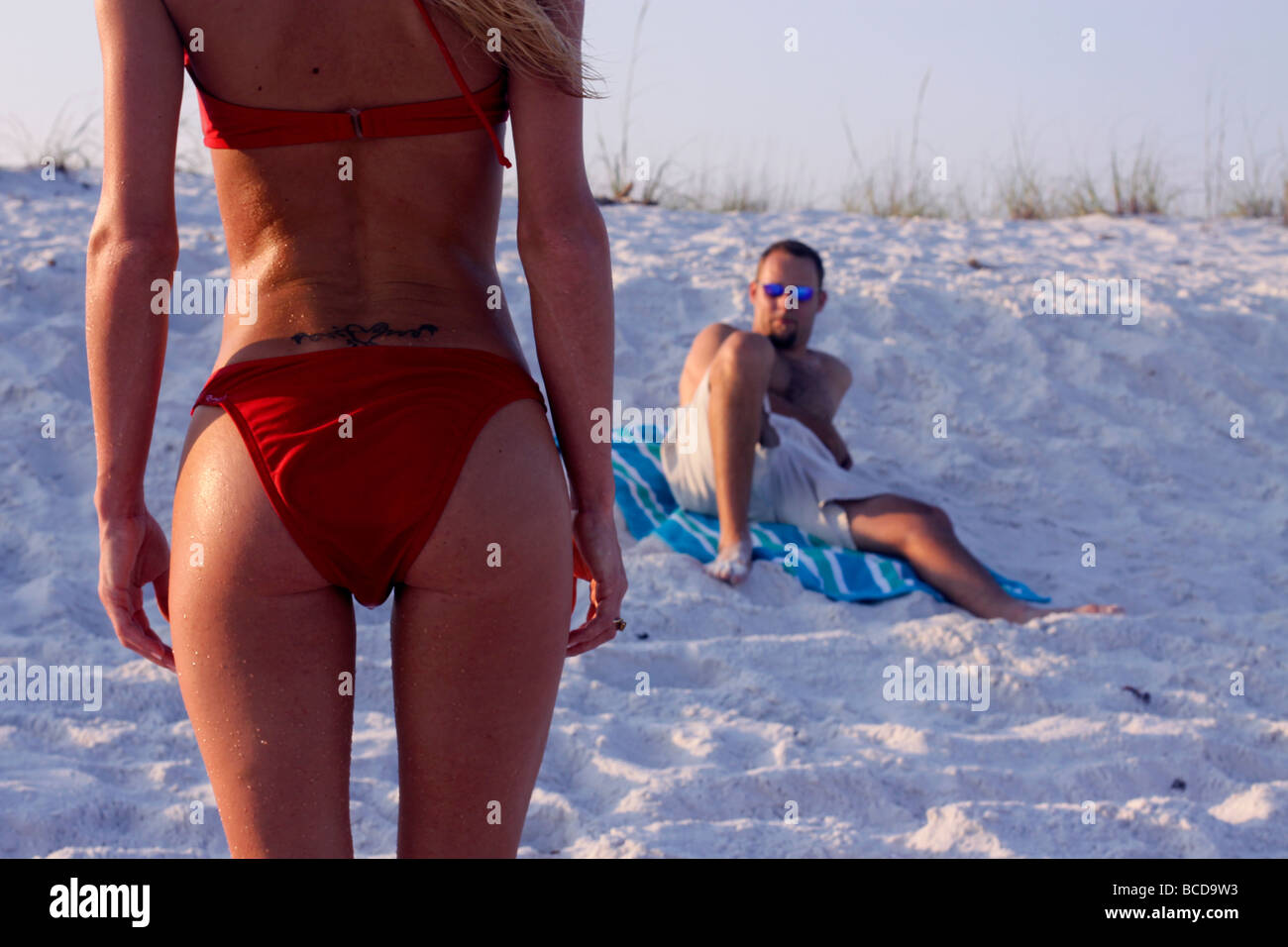 Sex-Appeal. Ein Mann in einem roten Bikini an einem Strand in Florida  Blickkontakt mit einer sexy attraktive Frau mit schöne Hintern  Stockfotografie - Alamy