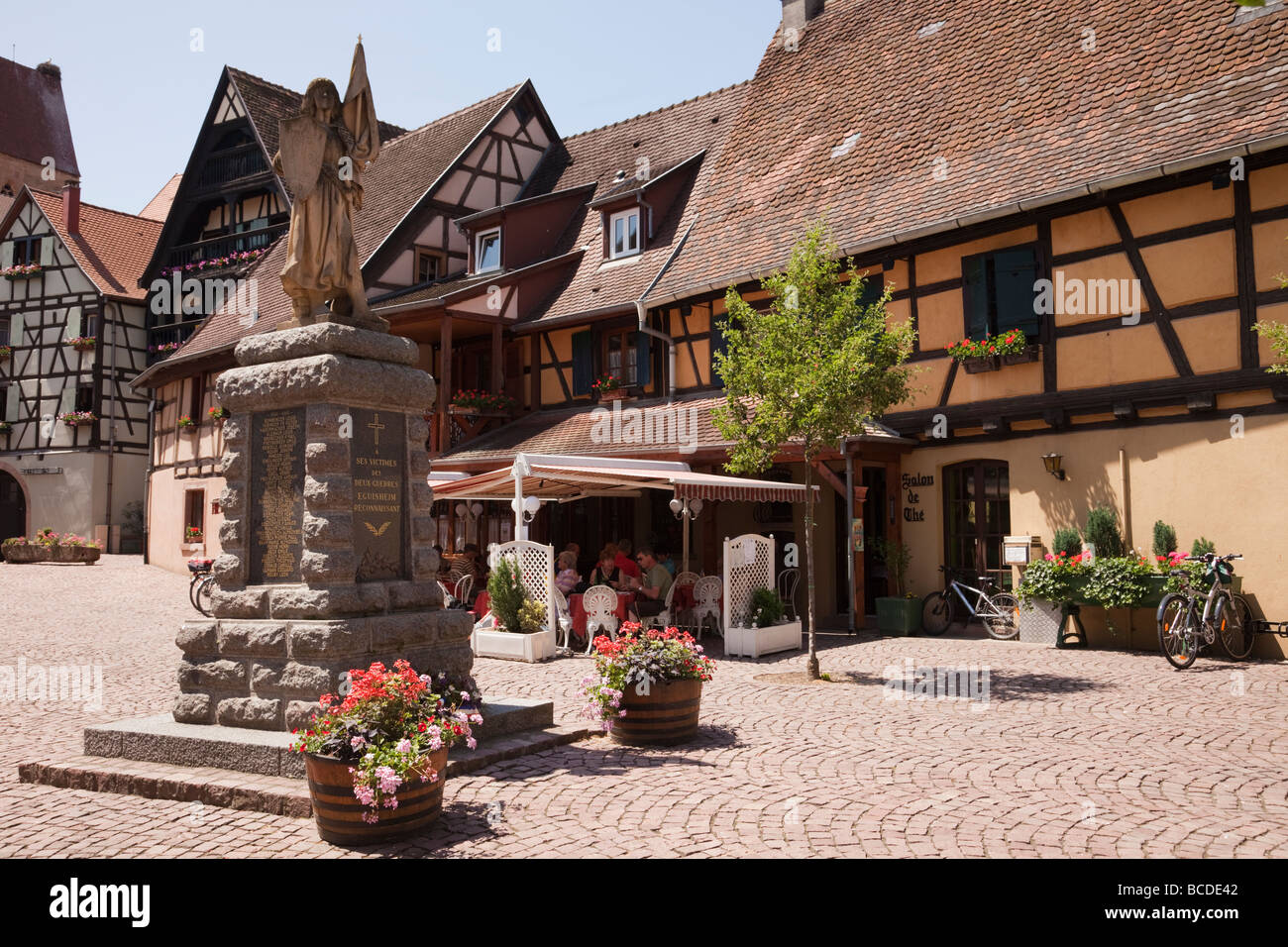 Kriegerdenkmal und Fachwerkbauten in mittelalterlichen Dorfplatz an der Weinstraße. Eguisheim Elsass Frankreich. Stockfoto