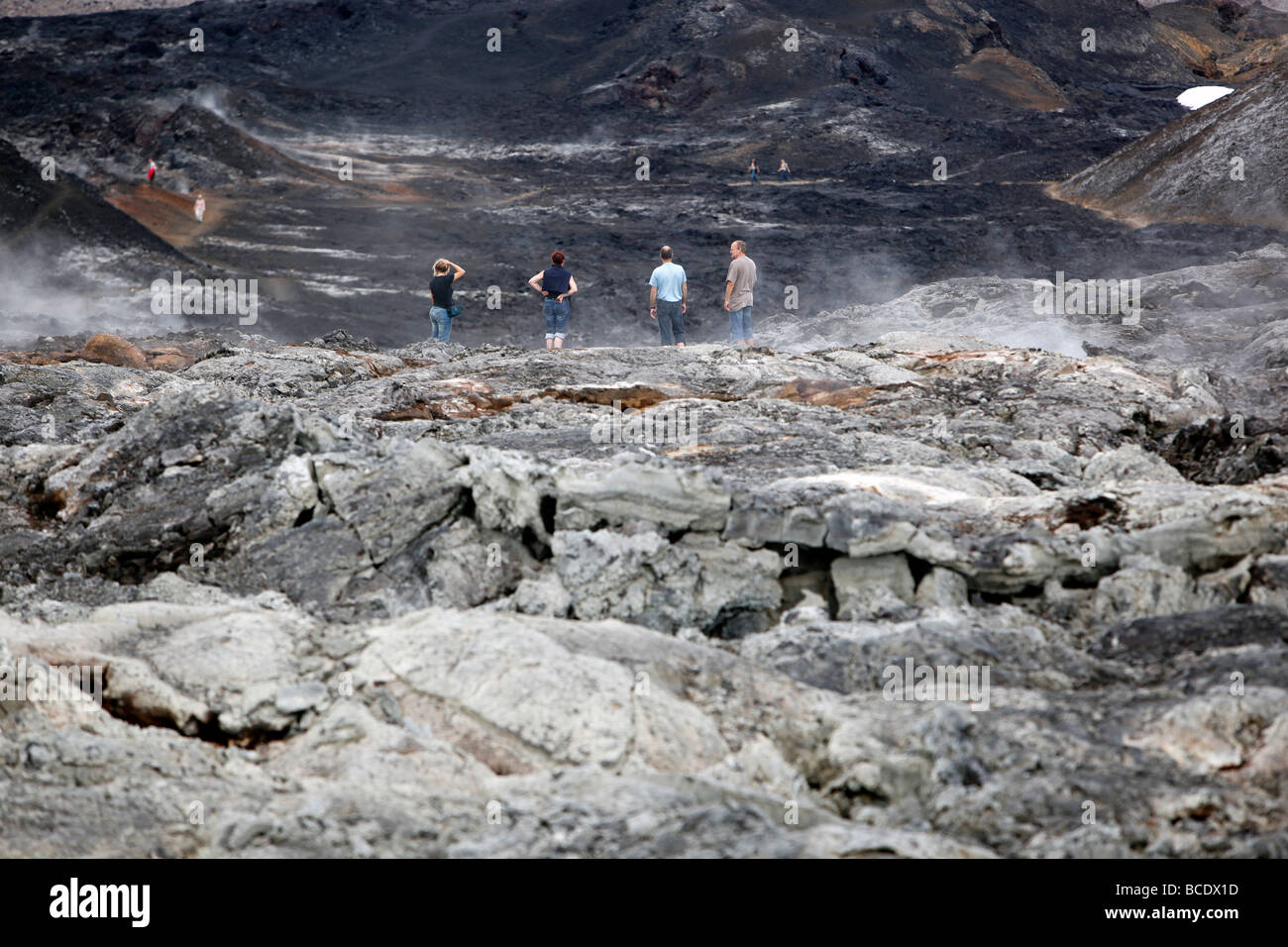 Vier Leute schauen auf einem Lavafeld, Krafla, Island Stockfoto