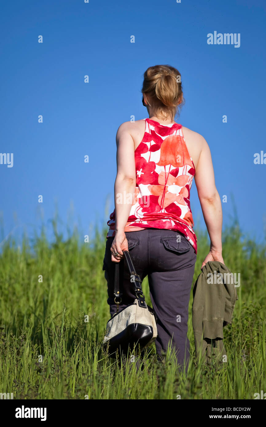 Rückansicht der Frau, die im hohen Gras, Manitoba, Kanada, spazieren geht. Stockfoto