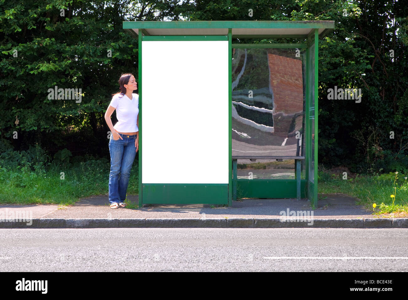 Frau stehend an einer Bushaltestelle mit leeren Plakatwand für Ihre eigene Nachricht Stockfoto