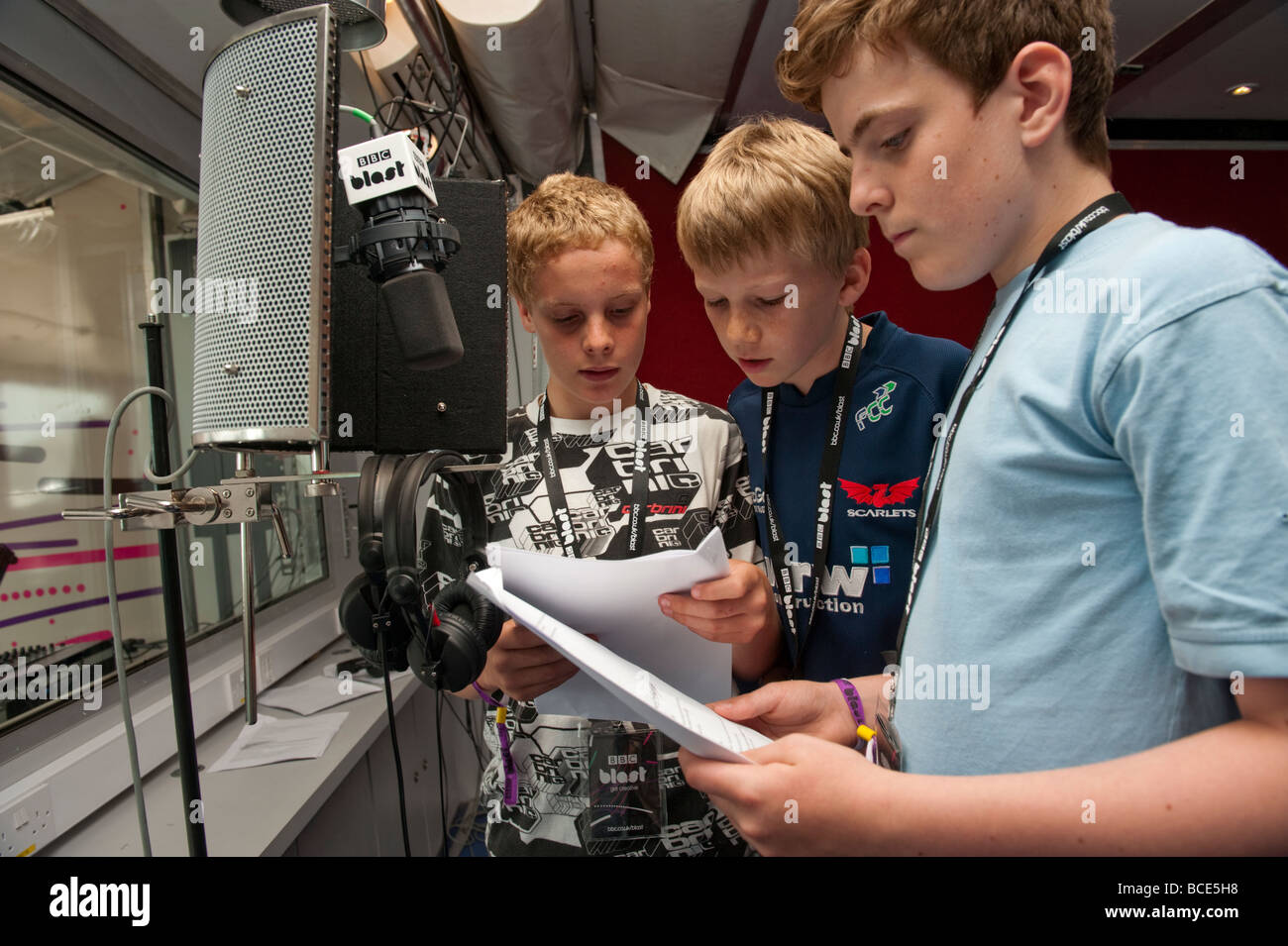 Drei Jungs im Teenageralter halten Skripte, die Aufnahme einer Radiosendung auf BBC Blast Roadshow, UK Stockfoto