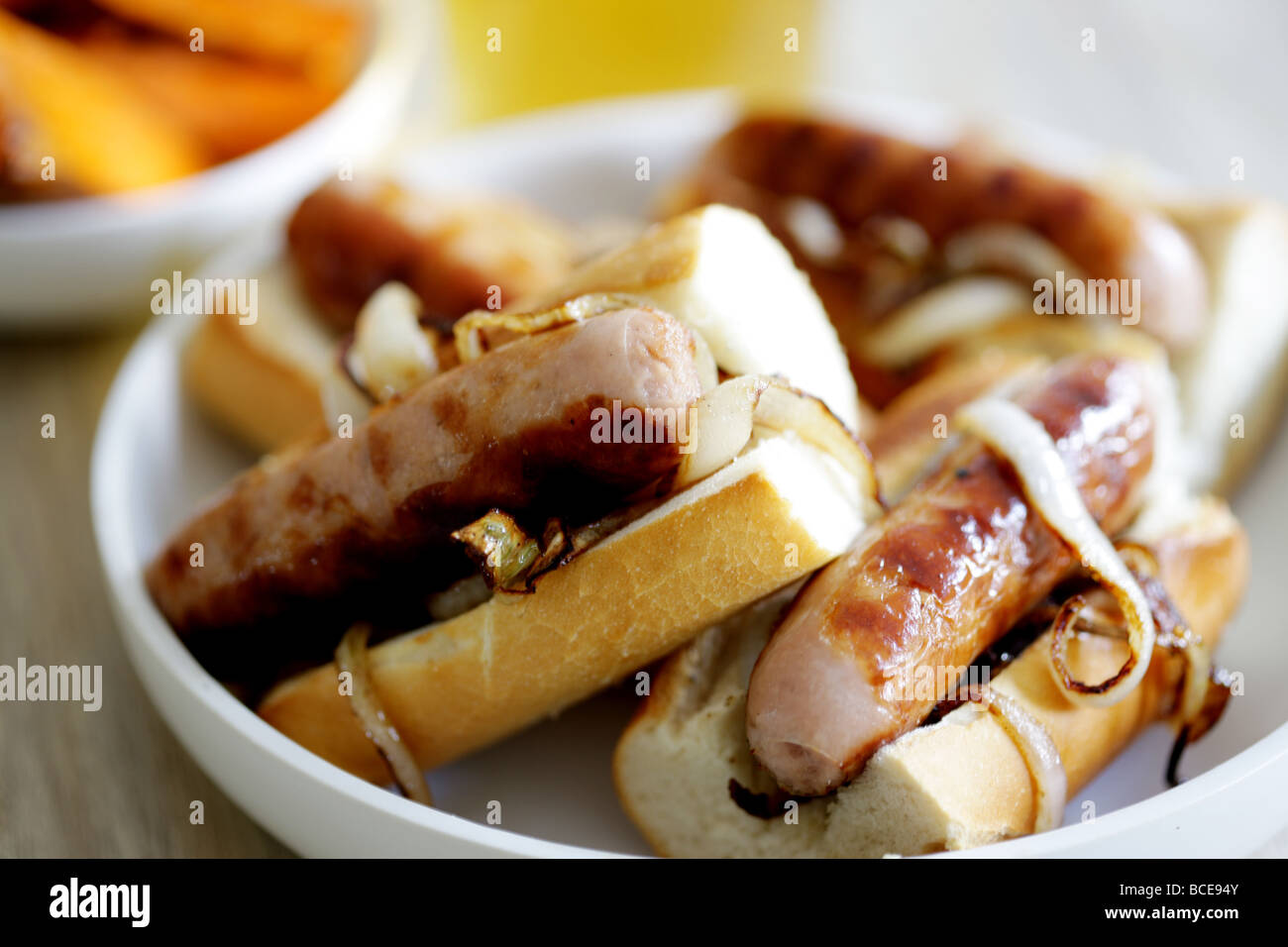 Frisch gekochte Wurst aus Schweinefleisch Hot Dogs mit Zwiebeln in einem weißen Brot Crusty Roll serviert in einer Schüssel mit Keine Personen Stockfoto