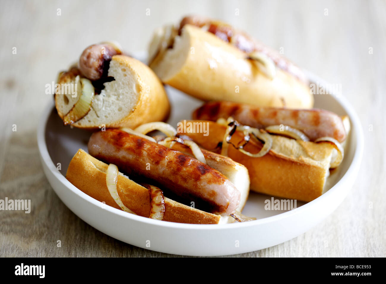 Frisch gekochte Wurst aus Schweinefleisch Hot Dogs mit Zwiebeln in einem weißen Brot Crusty Roll serviert in einer Schüssel mit Keine Personen Stockfoto