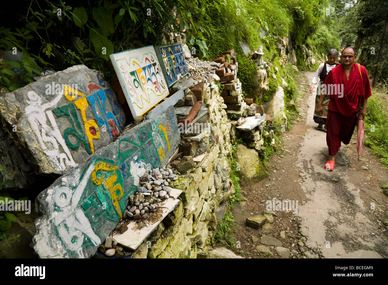 Buddhistischen tibetischen Mönch geht Vergangenheit, die Mani Steinen auf Kora Weg rund um den Tsuglagkhang Komplex. McCleod Ganj. Himachal Pradesh. Indien Stockfoto