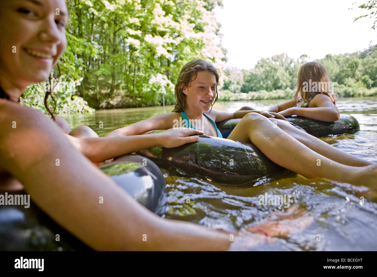 Jugendliche sitzen in Innertubes im Wasser Stockfoto
