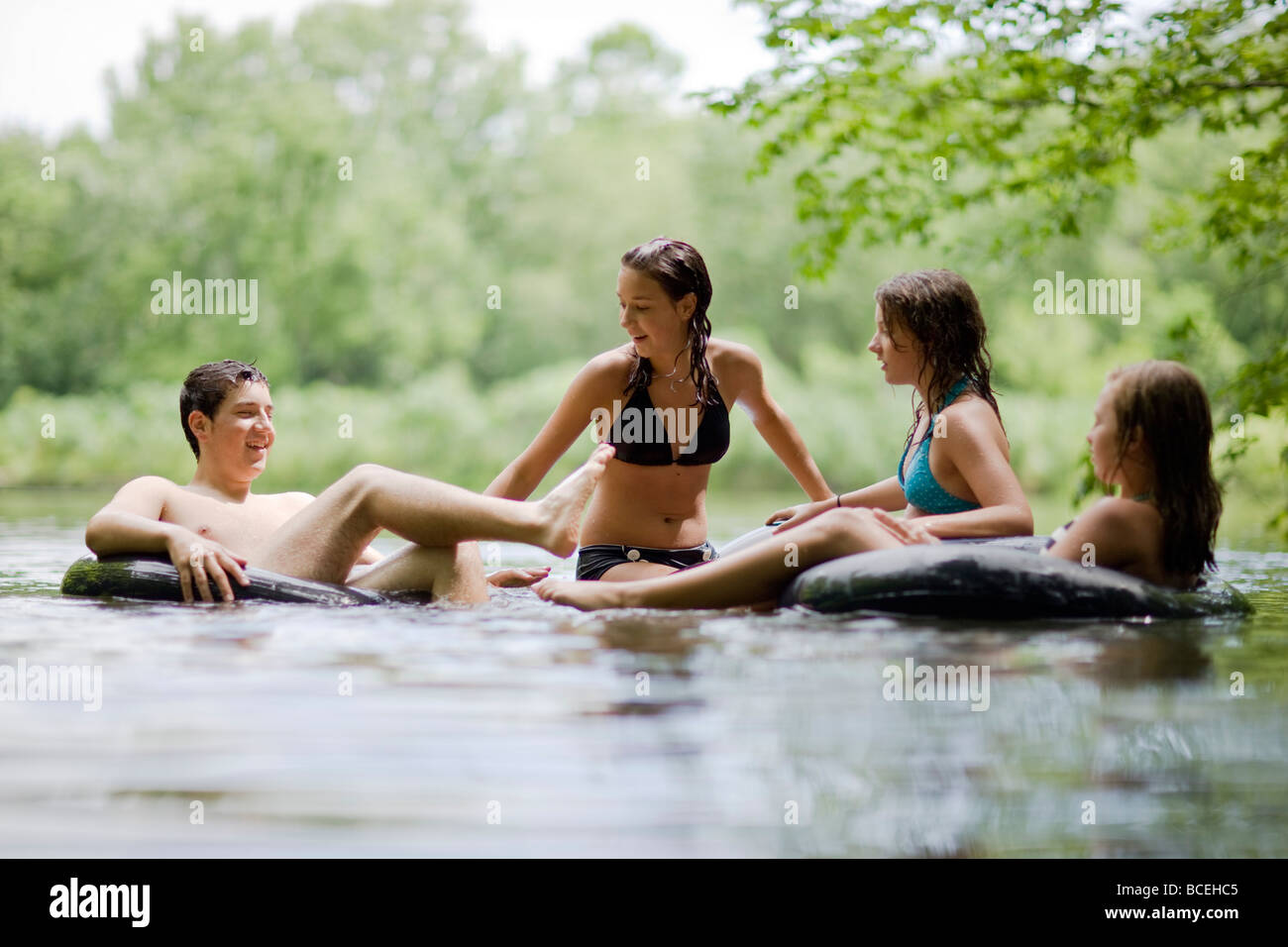 Jugendliche, die Spaß in Innertubes im Wasser Stockfoto