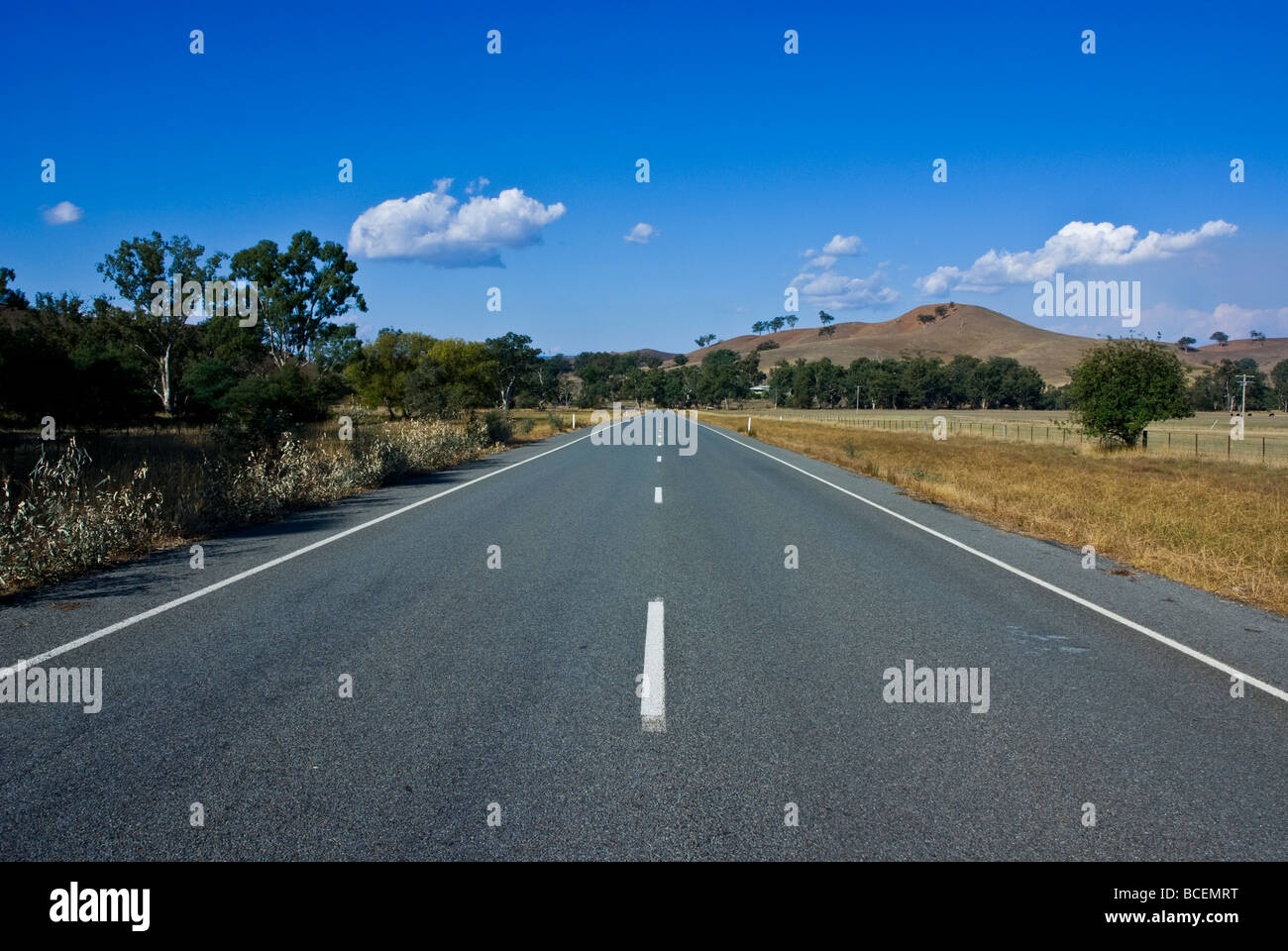 An empty country road passes through farmland and rolling hills. Stockfoto