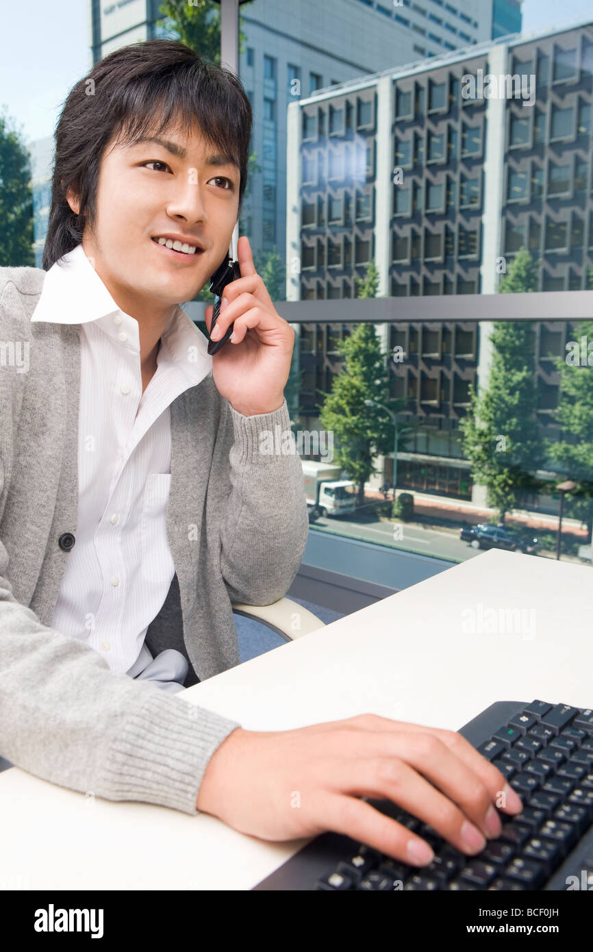 Junger Mann im Gespräch über Mobile Telefon im Büro Stockfoto