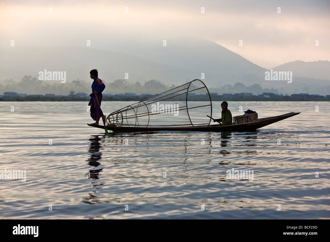 Myanmar, Burma, Lake Inle. Ein Intha Fischer mit traditionellen Fischfalle verwendet eine ungewöhnliche Bein Rudern Technik Stockfoto