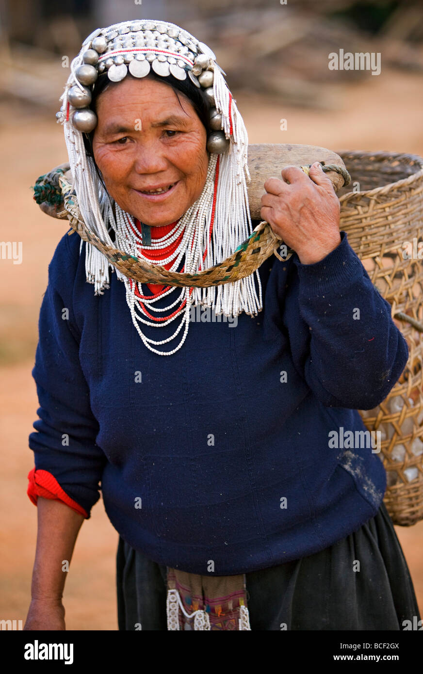 Myanmar, Burma, Namu-Op. Eine Akha Frau trägt einen großen Bambuskorb an der Rückseite ihres Halses durch ein Joch unterstützt. Stockfoto