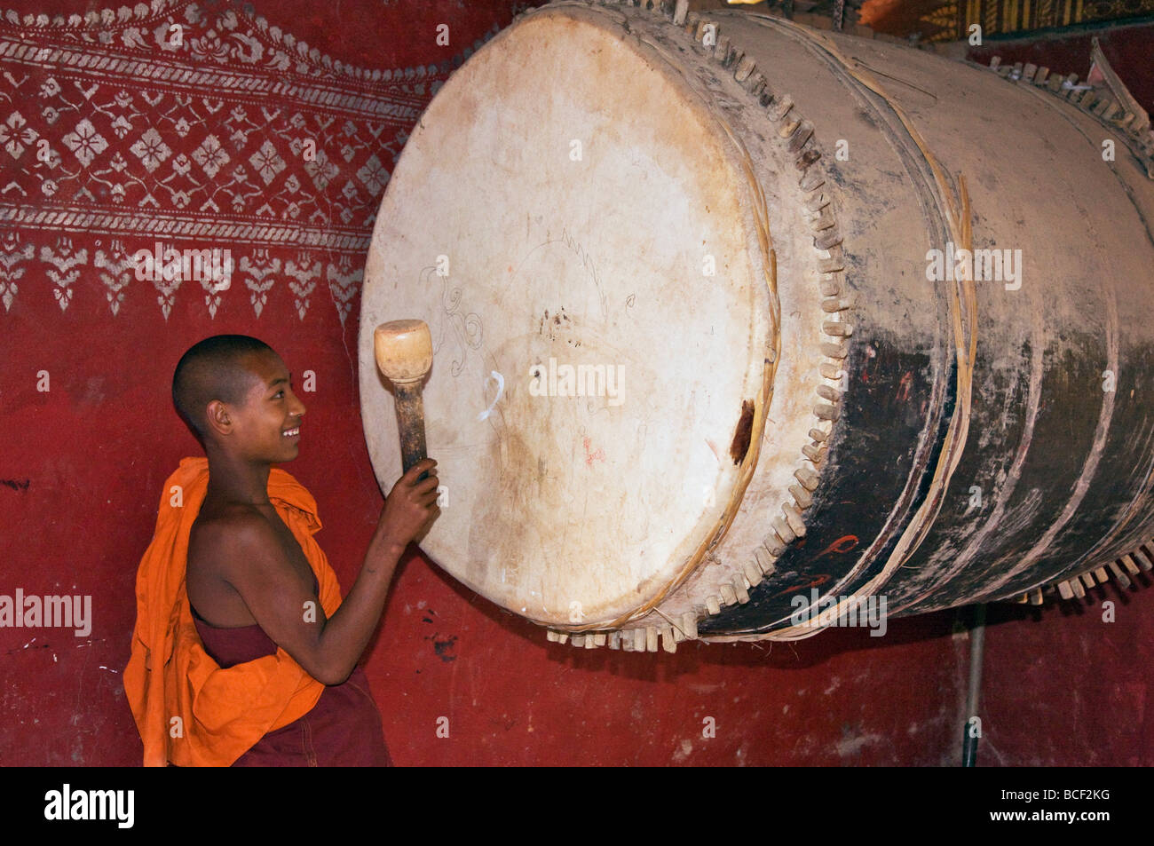 Myanmar, Burma, Wan-seeing.  Ein Novize schlägt die große Trommel im Inneren des wunderschönen Wan-seeing Klosters. Stockfoto