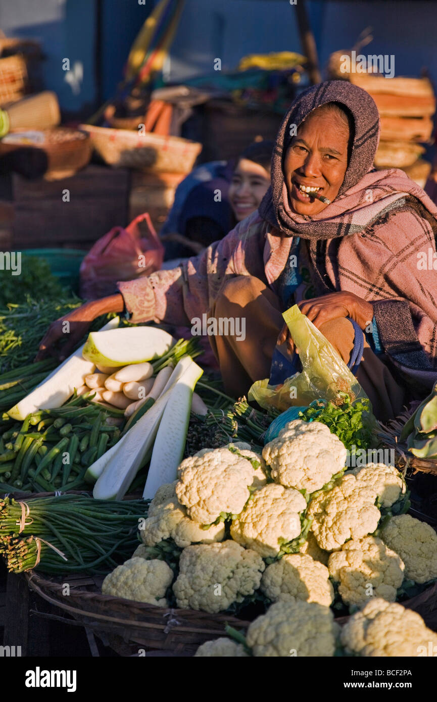 Myanmar, Burma, Rakhine-Staat. Eine Frau raucht eine Cheroot verkauft frisches Gemüse in einem Stall in Sittwe s geschäftigen Markt. Stockfoto Myanmar, Burma, Rakhine-Staat. Eine Frau raucht eine Cheroot verkauft frisches Gemüse in einem Stall in Sittwe s geschäftigen Markt. Stockfoto