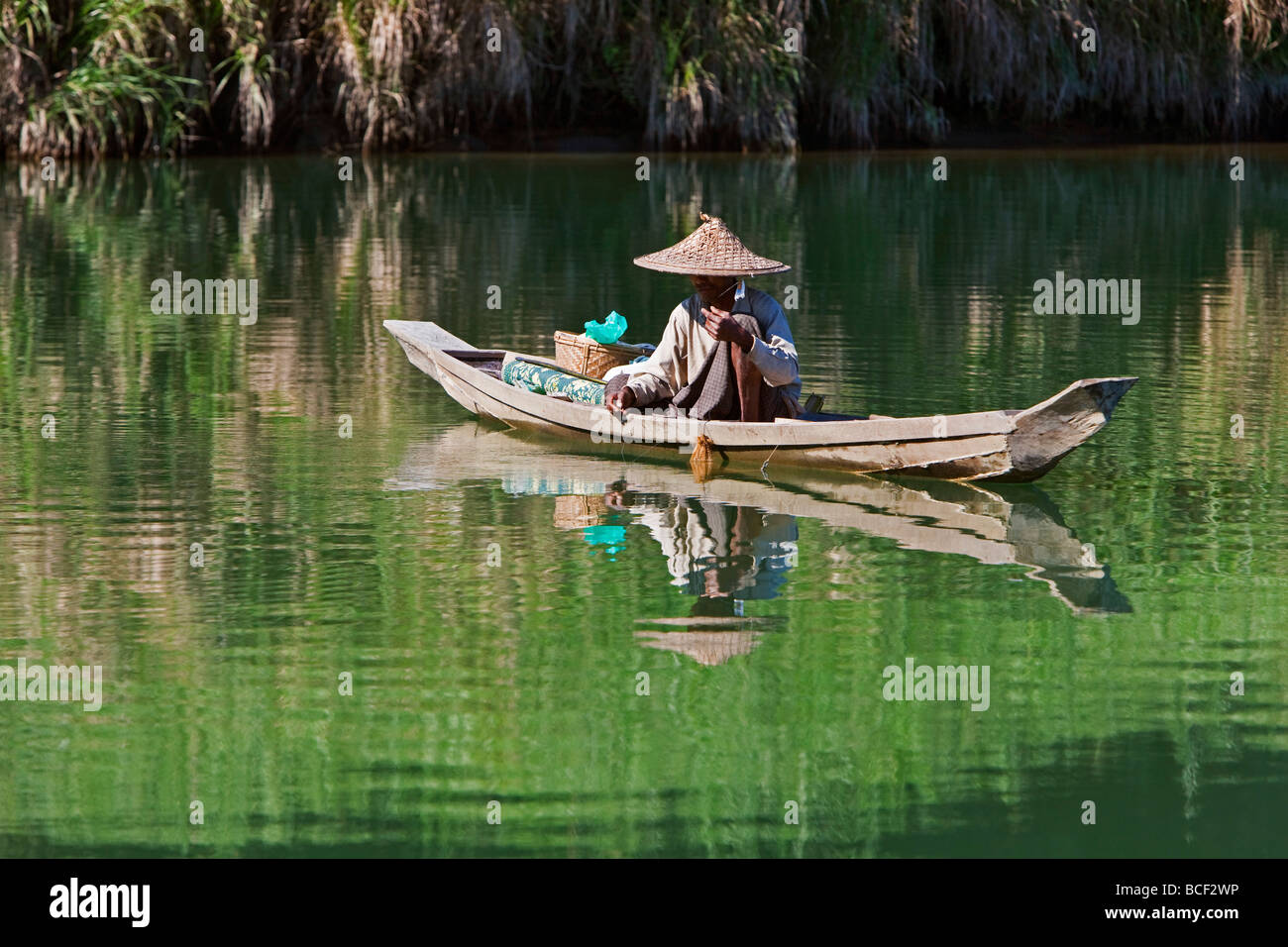Myanmar, Burma, Lay Mro Fluss. Ein Mann Rakhine Fische aus einem kleinen Holzboot in den stillen Wassern des Flusses Lay Myo. Stockfoto