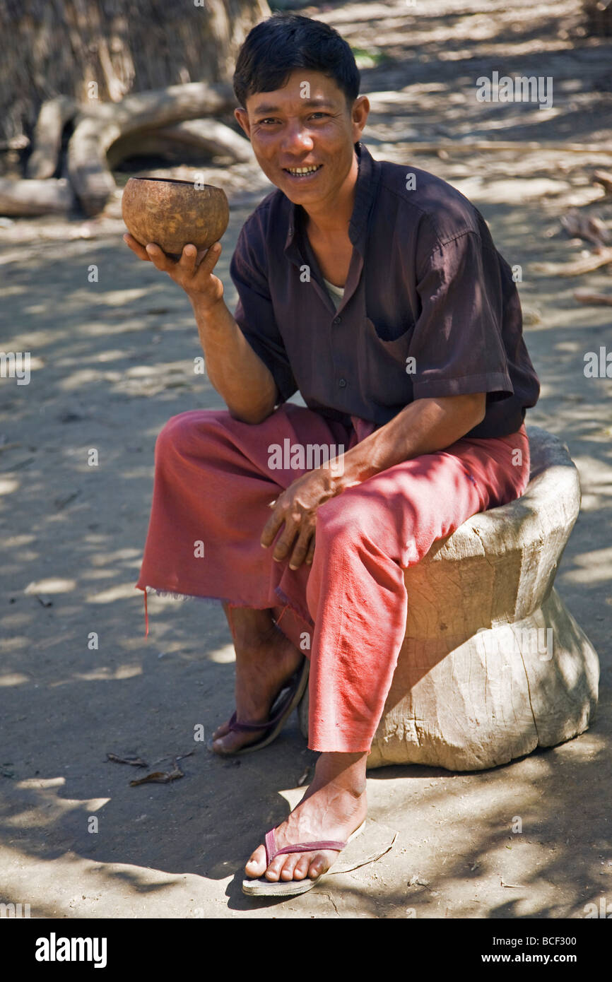 Myanmar, Burma, Rakhine-Staat Laung Shein. Ein junger Mann bei Laung Shein trinkt ein Getränk aus einem Becher aus einer Kokosnuss hergestellt. Stockfoto