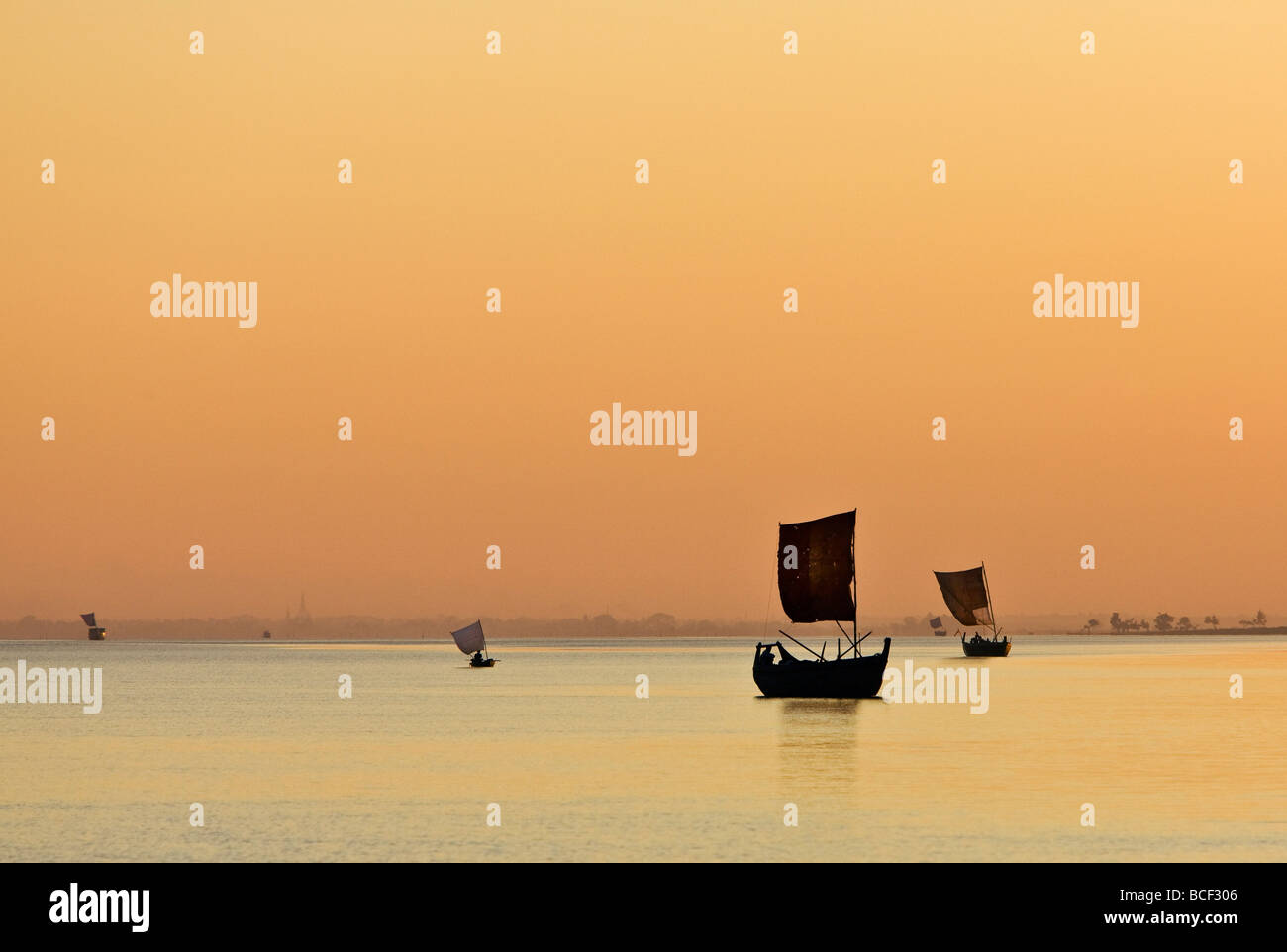 Myanmar, Burma, Rakhine-Staat Kaladan Fluss. Einen goldenen Sonnenuntergang am Fluss Kaladan als Segelboote Leiter für Zuhause. Stockfoto