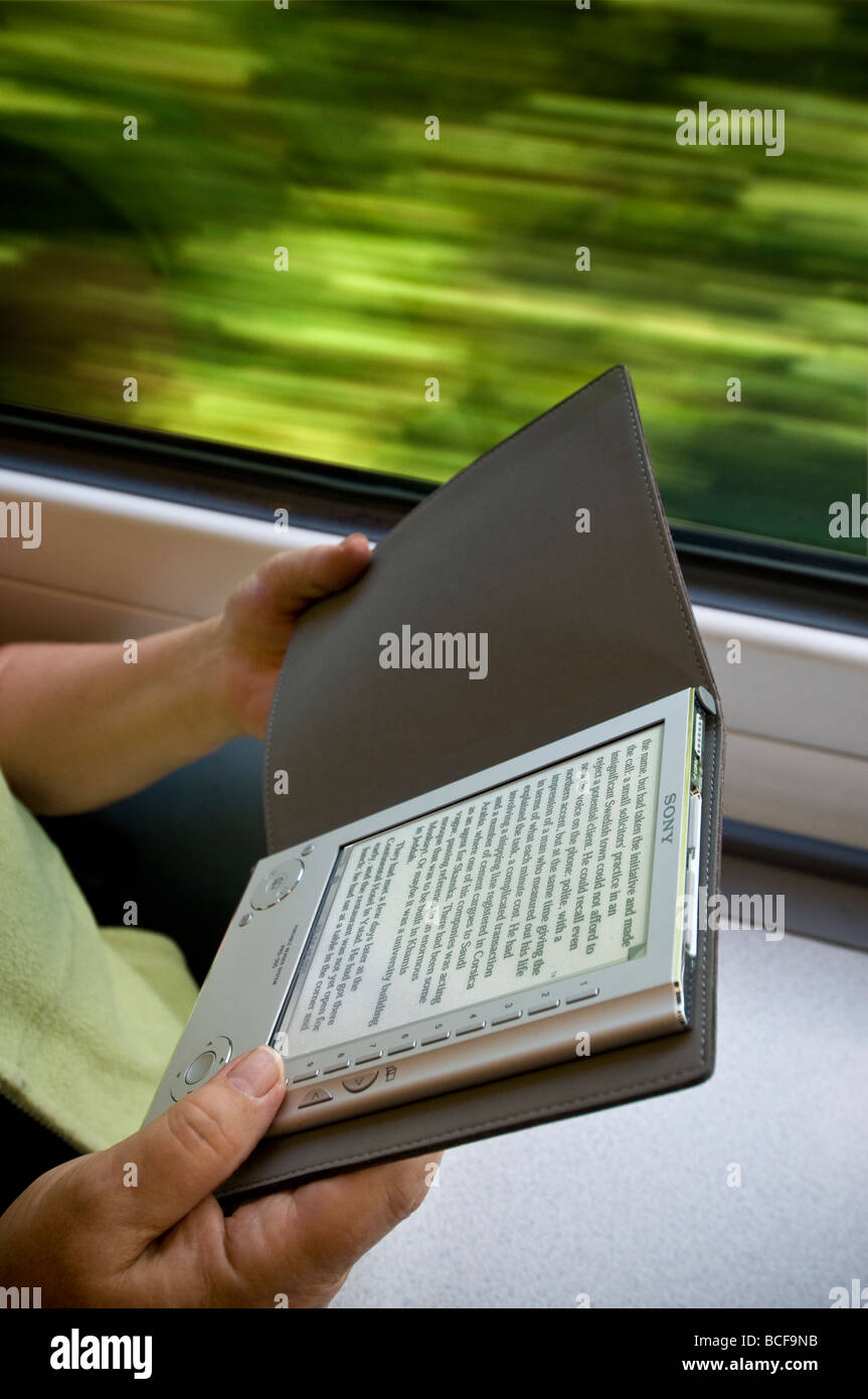 Sony eReader tragbare elektronische eBook-Lesegerät, Hände halten, in Zugwagen mit Bewegungsgeschwindigkeit verschwommen Hintergrund Stockfoto