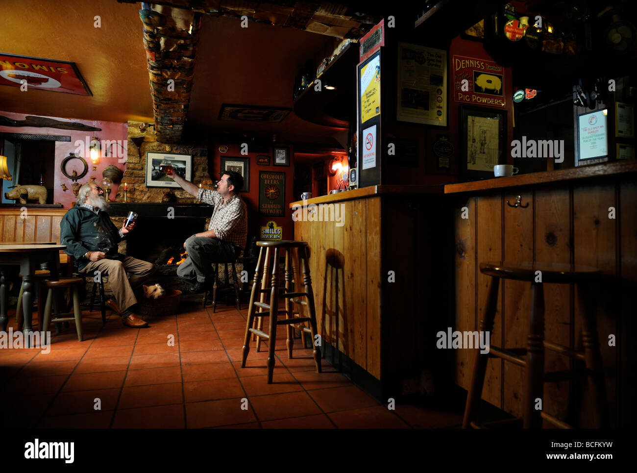 ZWEI MÄNNER IM CHAT AM OFFENEN KAMIN IN EINEM TRADITIONELLEN PUB GLOUCESTERSHIRE ENGLAND UK Stockfoto