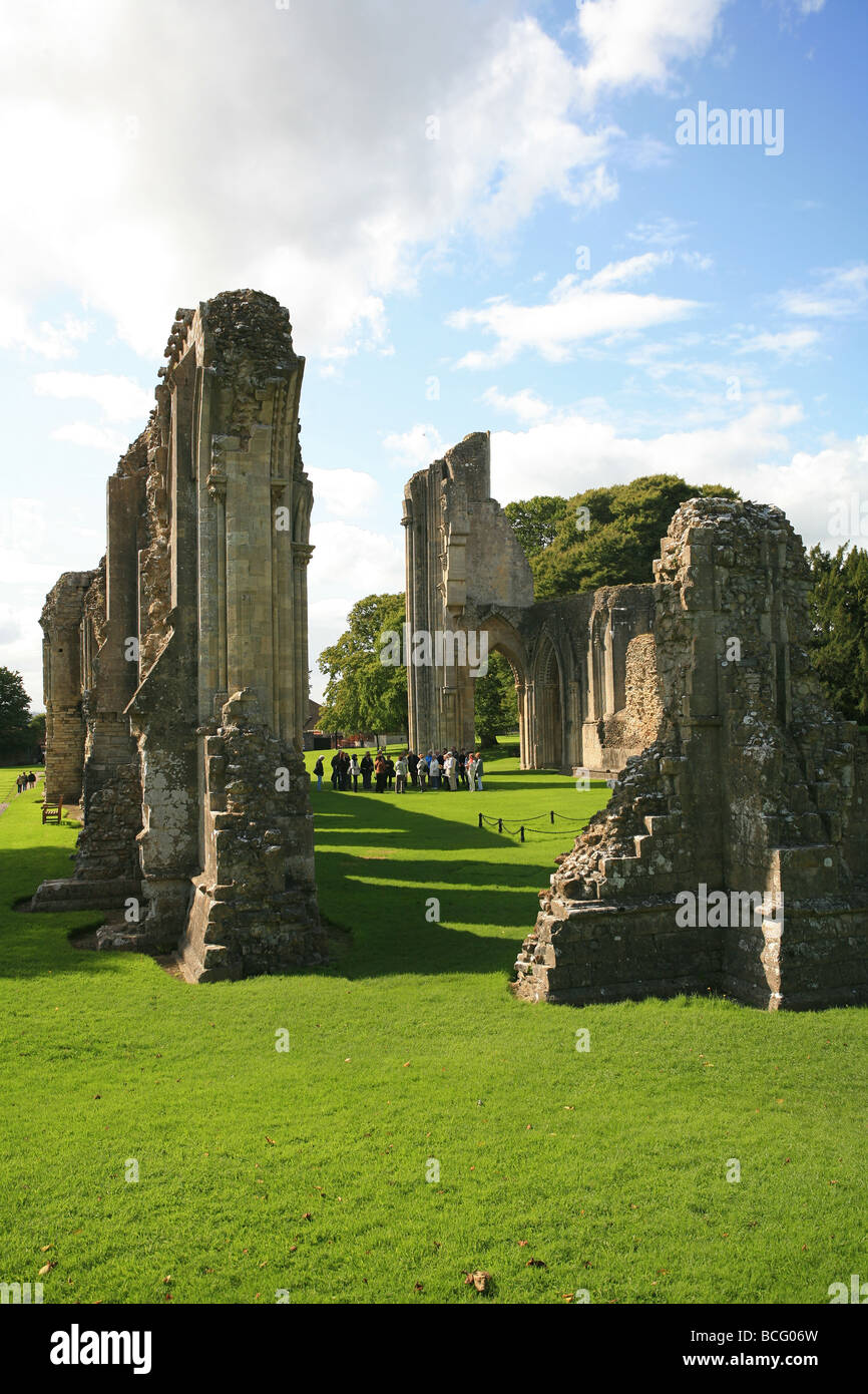 Eine Gruppe von Besuchern bekommen eine Führung von Glastonbury Abbey Ruinen, Somerset, England, UK Stockfoto