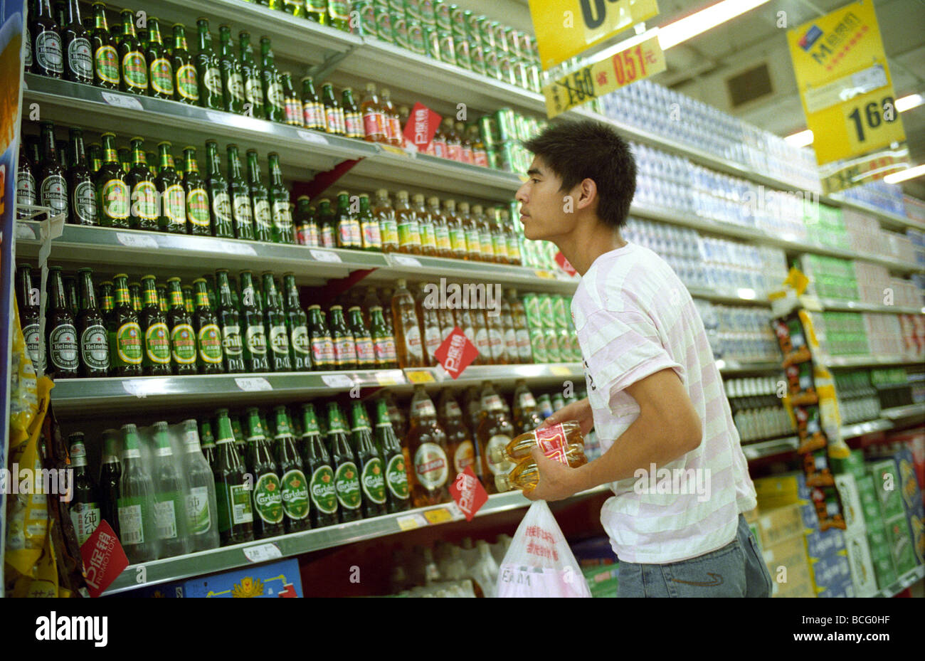 Chinesischer Mann Einkaufen an der Bier-Theke bei Tesco-Supermarkt in Peking, China. 2009 Stockfoto