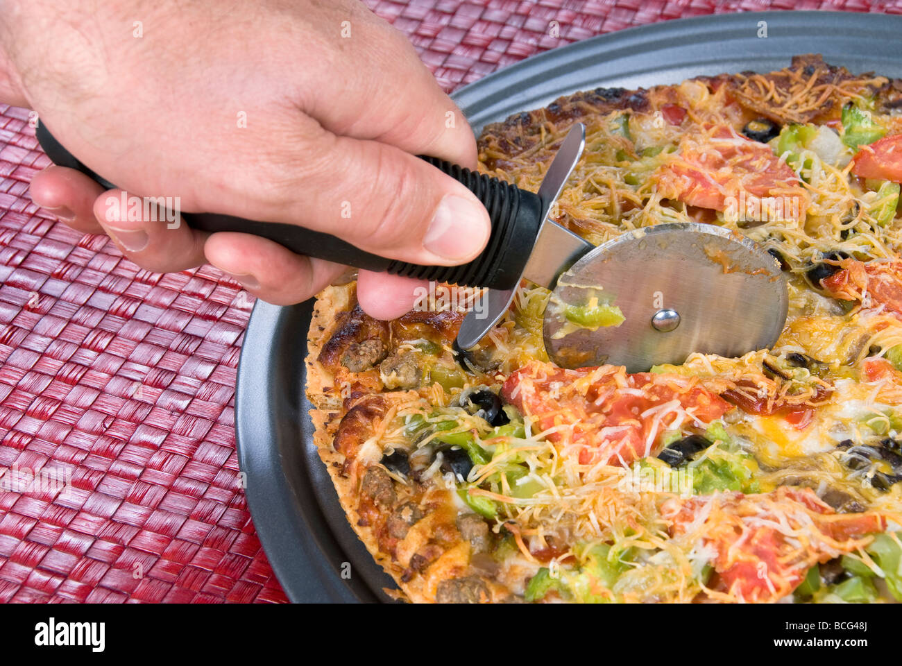 Eine heiße, die alle Werke Pizza mit einem scharfen Pizza Cutter geschnitten wird Stockfoto