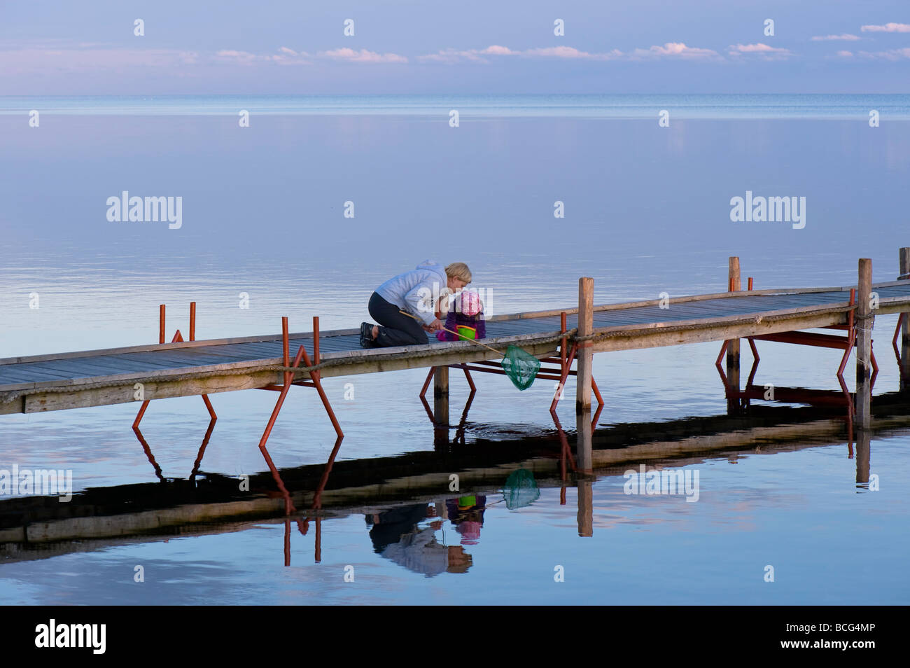 Mutter und Tochter auf Holzsteg mit Blick auf Bucht von Puck am frühen Abend Hel Halbinsel Ostsee Polen Stockfoto