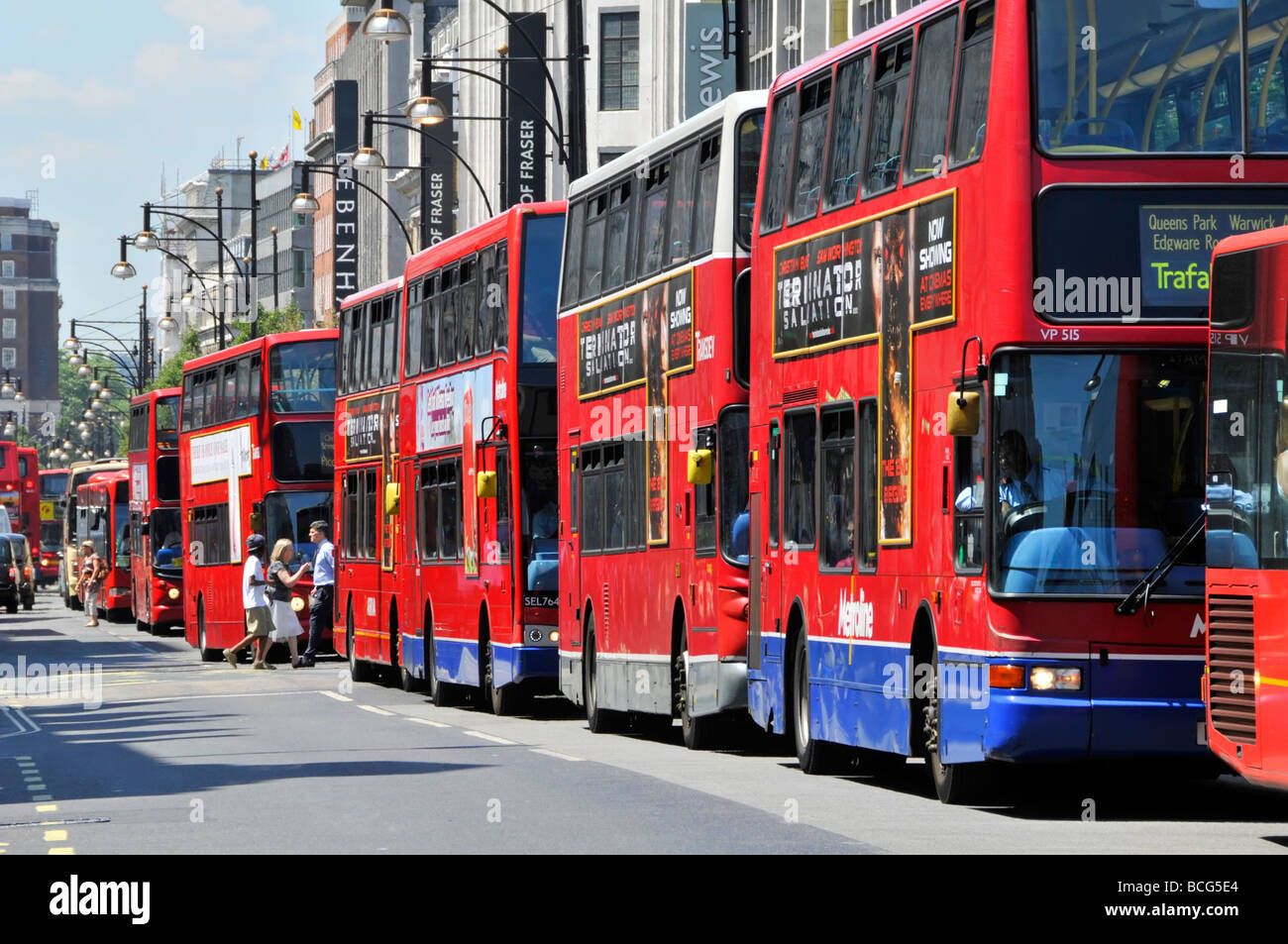 Fußgänger, die die Oxford Street zwischen einer langen Warteschlange roter Londoner öffentlicher Verkehrsmittel überqueren Doppeldeckerbusse sonnige Sommertage in West End England Großbritannien Stockfoto