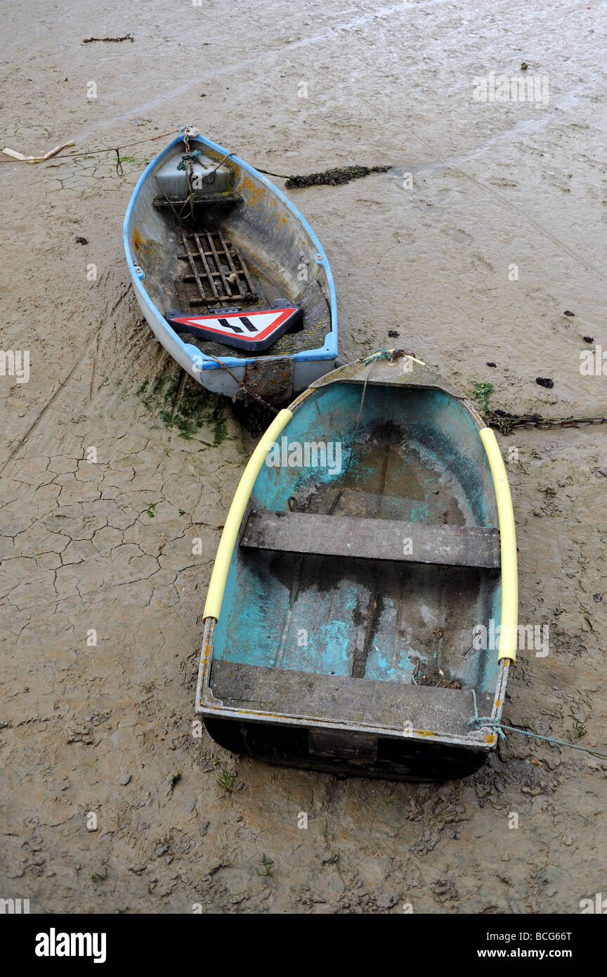 Ruderboote saßen bei Ebbe auf dem Schlamm im Fluss Adur bei Shoreham auf See in Sussex UK . Eine mit einem alten Straßenschild drin Stockfoto