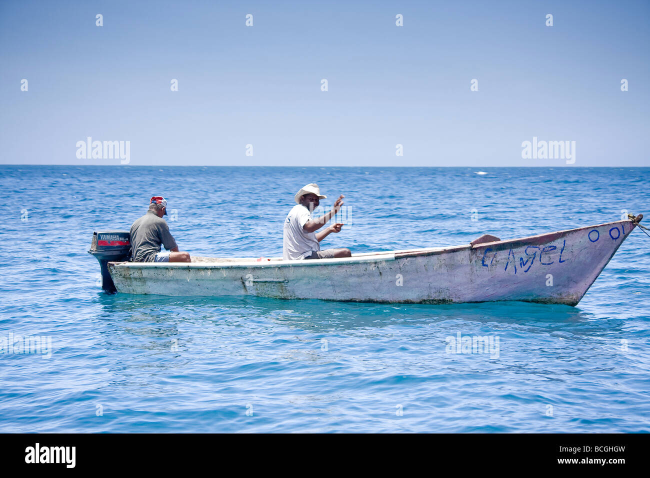 Zwei Männer Fisch von einem kleinen Boot in den klaren blauen Gewässern des Atlantischen Ozeans in der Nähe von Playa Grande Dominikanische Republik Stockfoto
