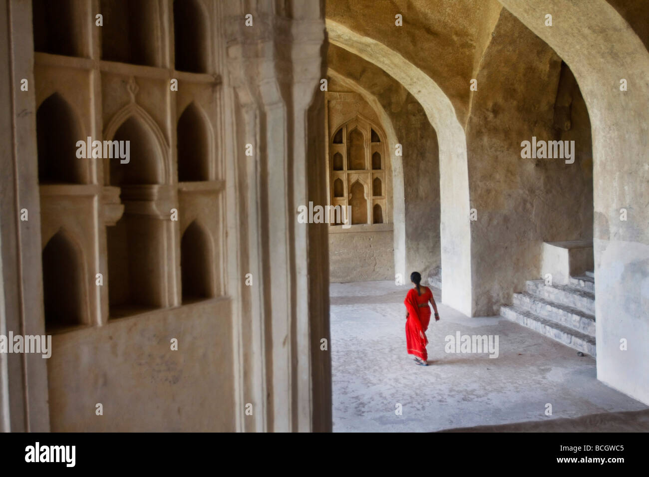 Eine indische Frau in einen traditionellen roten Sari Spaziergänge durch die Golcanda Fort, eine wichtige touristische Attraktion in Hyderabad in Indien. Stockfoto