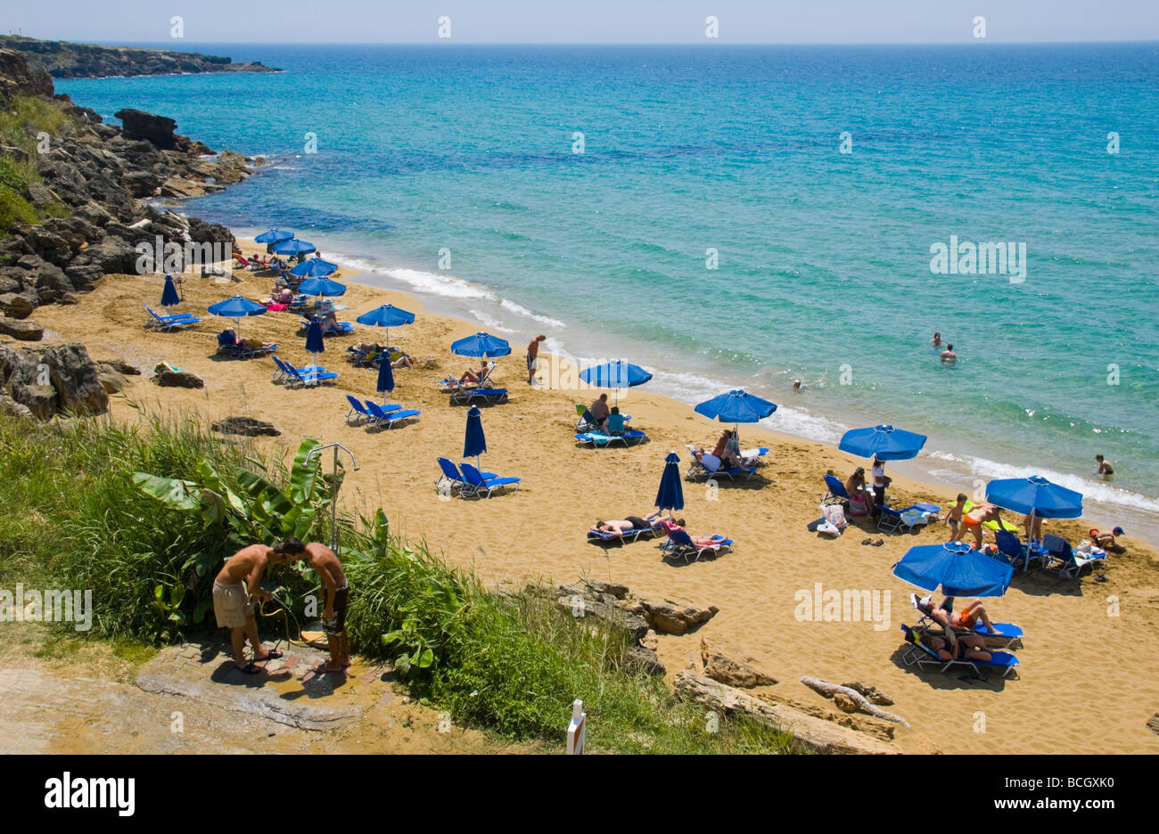 Entspannen Sie sich auf Liegestühlen unter Sonnenschirmen auf den kleinen Ammes-Sandstrand auf der griechischen Insel Kefalonia Griechenland GR Touristen Stockfoto