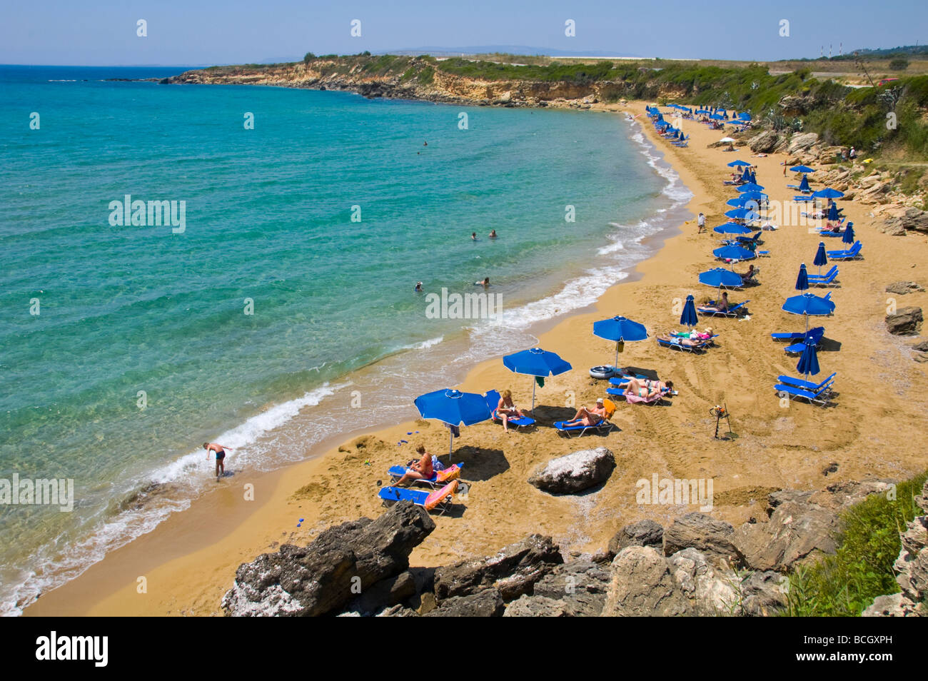 Entspannen Sie sich auf Liegestühlen unter Sonnenschirmen auf den kleinen Ammes-Sandstrand auf der griechischen Insel Kefalonia Griechenland GR Touristen Stockfoto