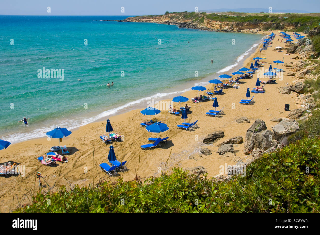 Entspannen Sie sich auf Liegestühlen unter Sonnenschirmen auf den kleinen Ammes-Sandstrand auf der griechischen Insel Kefalonia Griechenland GR Touristen Stockfoto