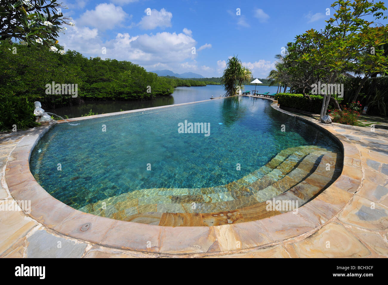Schwimmbad von einem tropischen Resort an einem See mit chaises Stockfoto