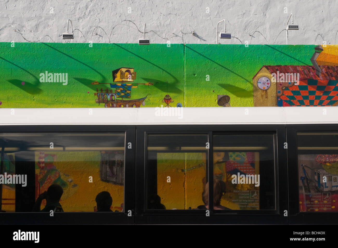 Passagiere im Bus sehen Os Gemeos Abschluss ein neues Wandbild an der Stelle des alten Keith Haring Wandbild Stockfoto