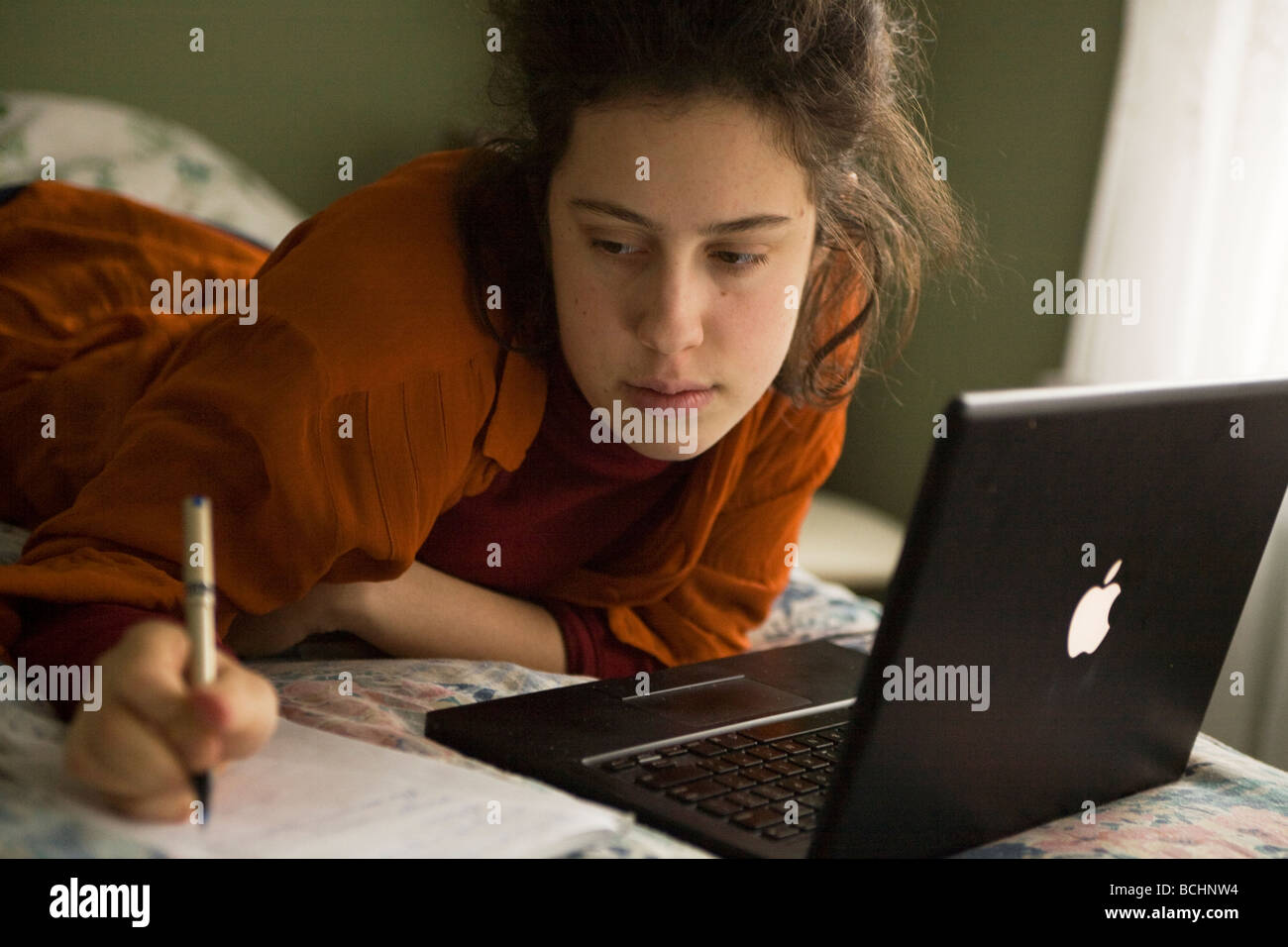 Weibliche College-Student arbeitet in einem drahtlosen Internet-Netzwerk auf ihrem Bett in New York City Stockfoto