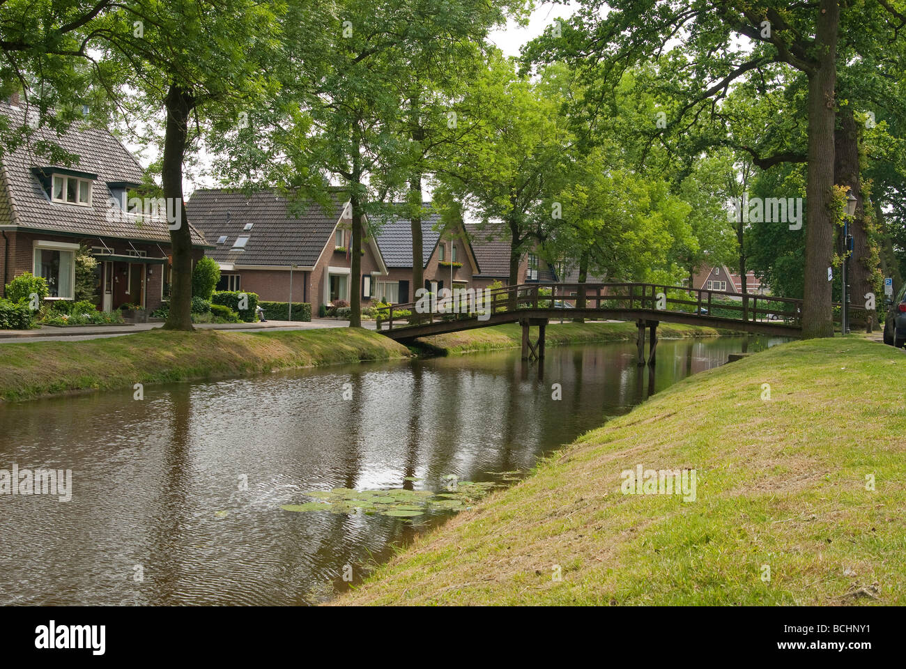 Alte Holzbrücke über einen Kanal in einer typisch holländischen Dorf-Szene Stockfoto