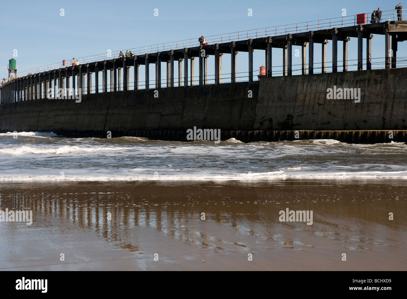 Wanderer auf der Hafenmauer gesehen vom Strand bei Whitby in North Yorkshire. Stockfoto