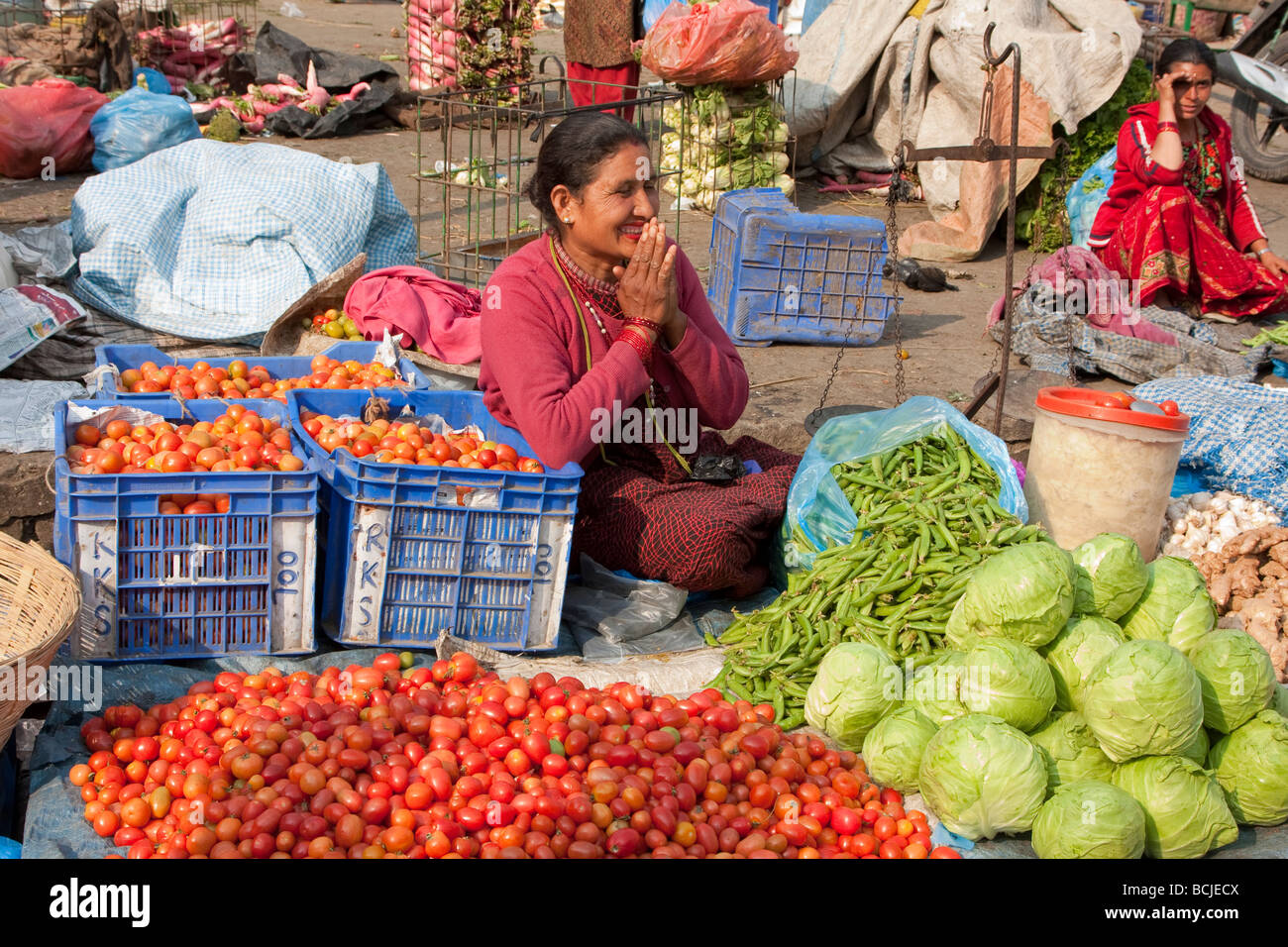 Kathmandu, Nepal.  Nachbarschaft Gemüsemarkt.  Ein Frau-Anbieter bietet einen traditionelle Namaste-Gruß. Stockfoto